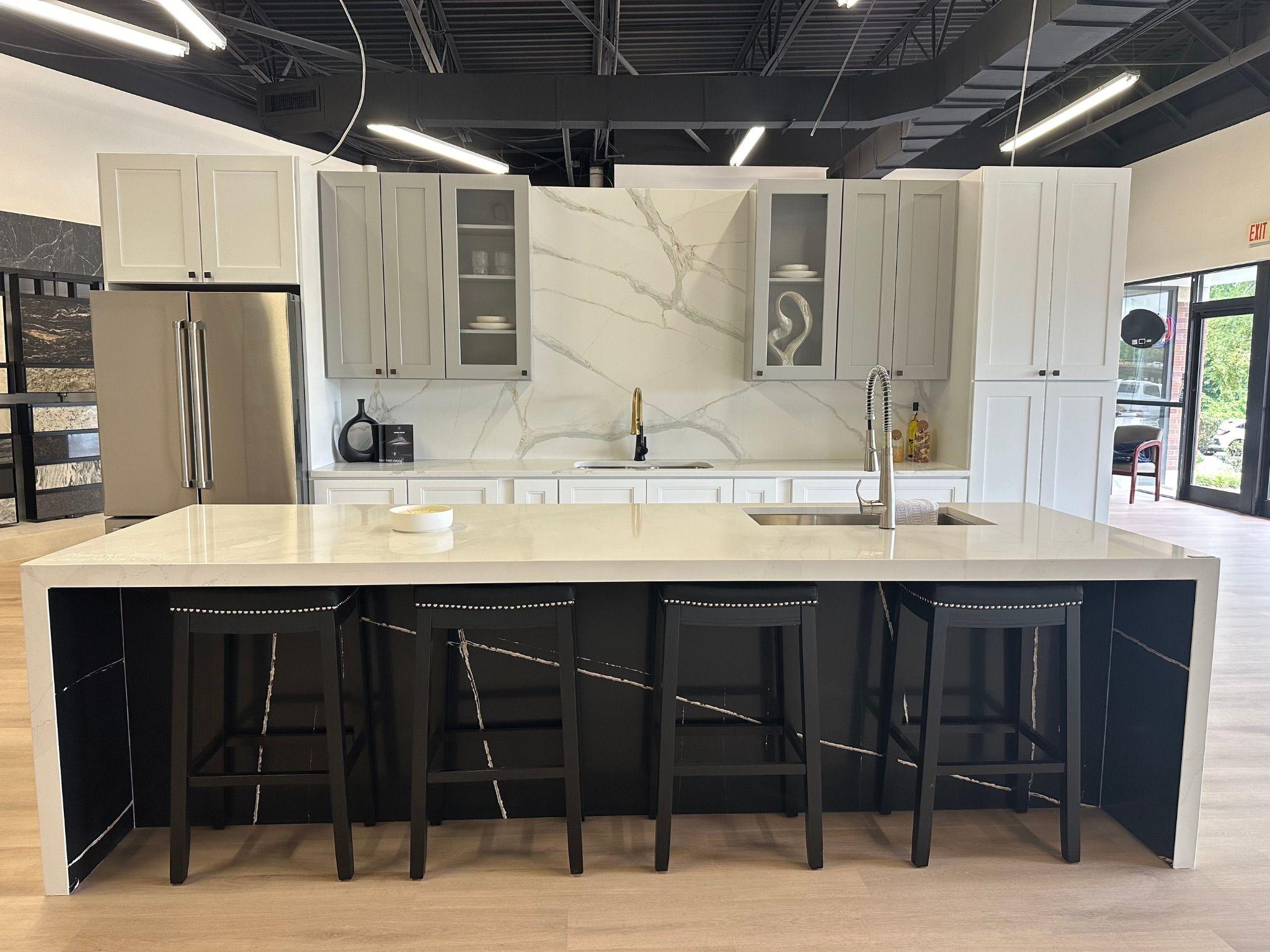 Full kitchen setup featuring a large island with bar seating, white countertops, and a marble backsplash. The modern space is completed with sleek cabinetry and stainless steel appliances.