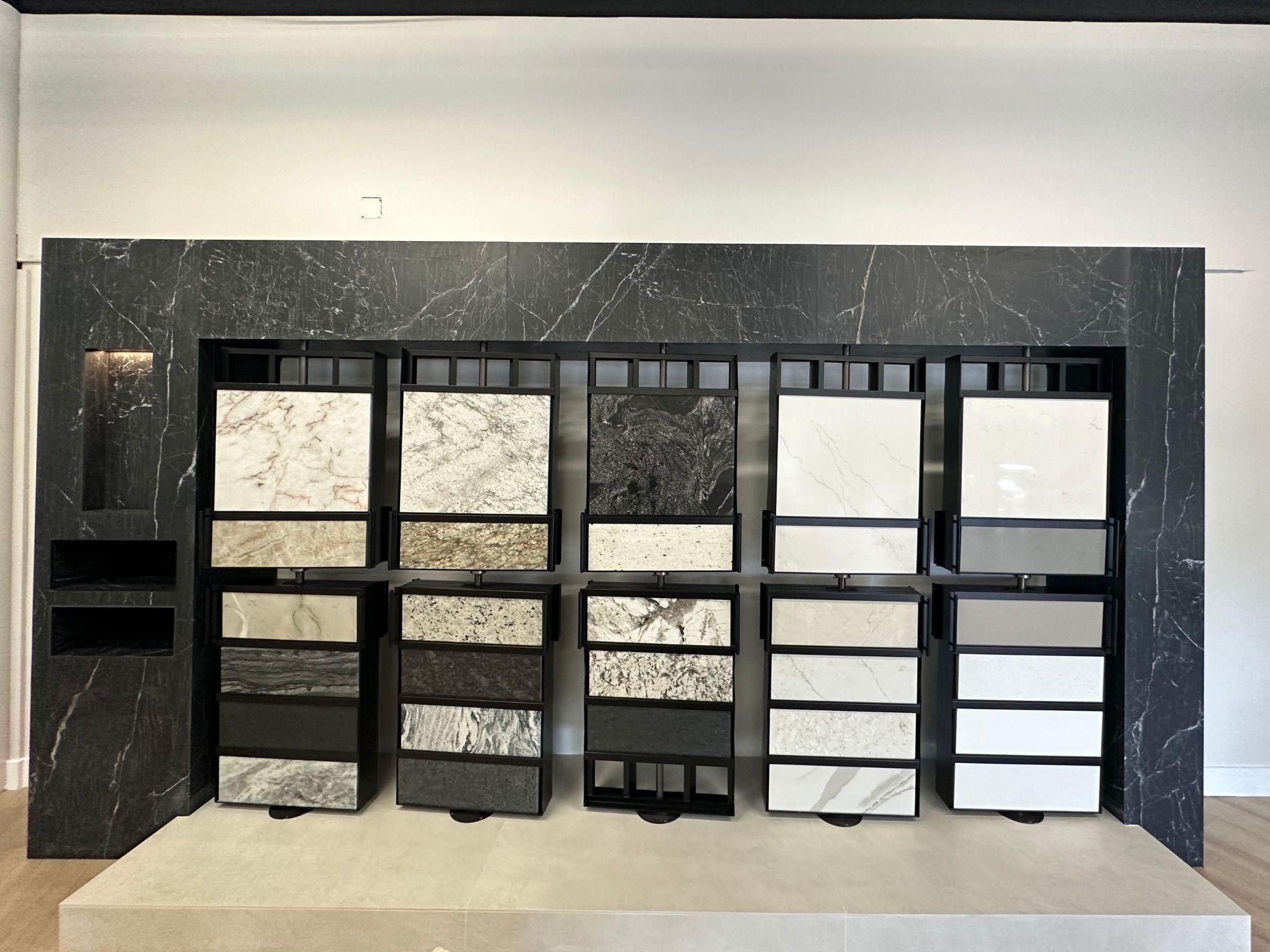 A countertop sample display wall showcasing a variety of natural and engineered stone slabs in different colors and patterns, framed by black accents for a sleek, modern look.